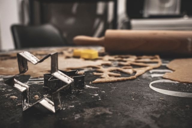 Star cookie cutters and a rolling pin on rolled dough