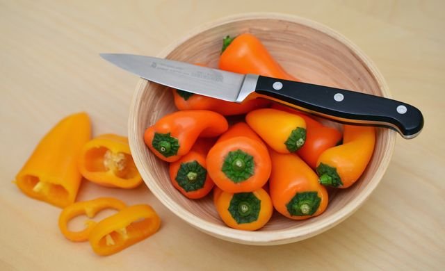 Paring knife resting on a bowl of mini peppers