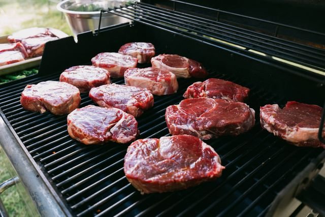 Raw steaks on the grill